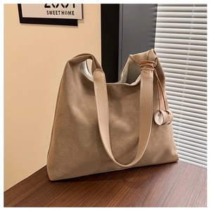 Detail of minimalist cream tote bag with brown leather rope pendant on wooden table