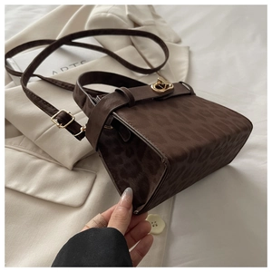 Detailed bottom view of leopard print shoulder bag with gold twist lock and matte texture