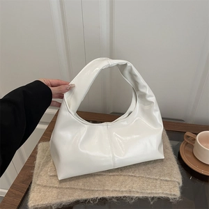 Minimalist white hobo bag in glossy patent leather with hobo silhouette on wooden table