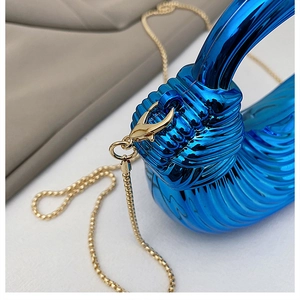Macro detail of electric blue pleated acrylic handbag with premium gold chain clasp