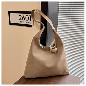 Detail view of large beige tote bag with soft leather texture and stylish metal charm