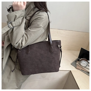 Dettaglio di una grande borsa tote in pelle scamosciata marrone con lacci laterali