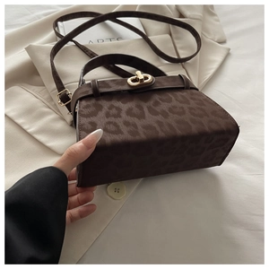 Detailed view of brown leopard print handbag with golden oval clasp and furry texture