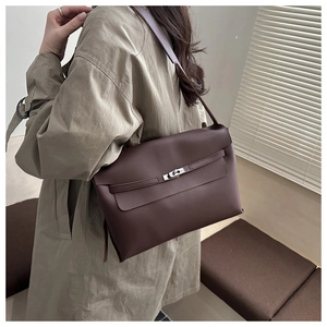 Detail of the turn-lock closure and belt strap on a dark brown leather crossbody bag