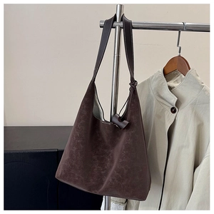 Detail of dark brown tote bag with vintage texture hanging on a metal hanger in a cozy setting
