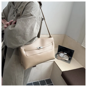Detail of minimalist beige leather crossbody bag with silver buckle in modern office setting