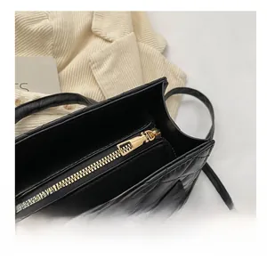 Detail of smooth gold zipper and quilted pattern on black faux leather crossbody bag