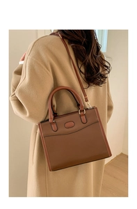 Borsa tote classica in pelle PU marrone portata a tracolla su un cappotto di lana cammello
