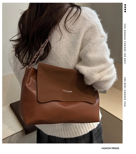 Detail of a brown shoulder bag with chain strap and 'FASHION & BAGS' lettering on a model