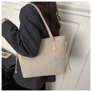 Dettaglio borsa tote beige con lacci rosa indossata su un cappotto di lana grigio