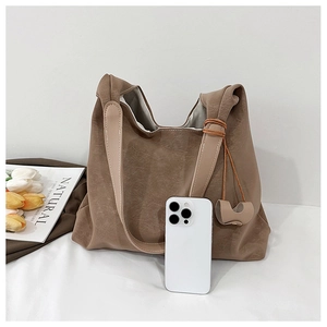 Detail of large brown tote bag with pebble leather texture and a smartphone for size reference
