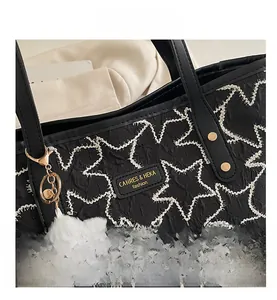 Detail of black tote bag featuring star quilting and golden brand nameplate