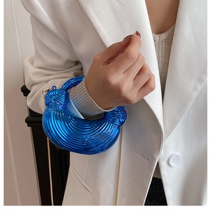 Close-up of bright blue acrylic handbag with textured ridges and elegant gold chain strap