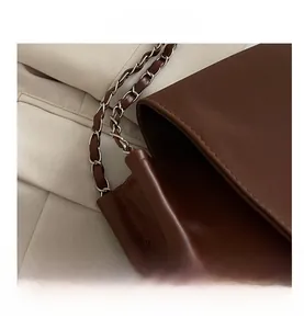 Detail of vintage brown leather tote with intertwined chain shoulder strap and matte finish