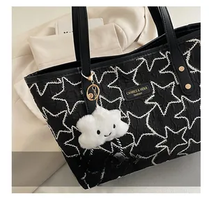Detail of black tote bag with white star patterns and cute cloud charm accessory