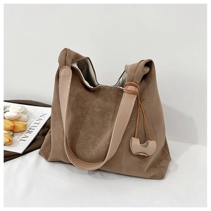 Close-up of vintage brown leather tote bag with pleated texture and decorative pendant