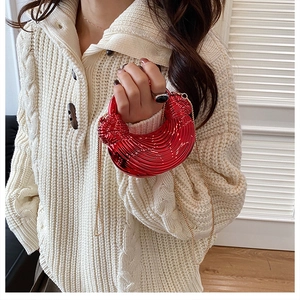 Close-up of metallic red pleated evening bag with gold chain and moon-shaped texture
