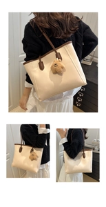Detail view of large beige tote bag with brown handles and a plush bear accessory