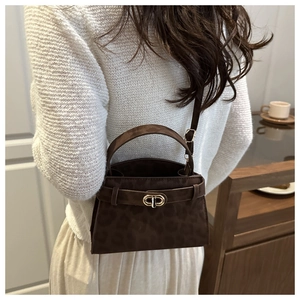 Brown leopard print suede handbag shown with gold ring clasp and adjustable strap on a model