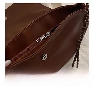 Detail of dark brown leather chain bag showing smooth metal zipper and magnetic closure