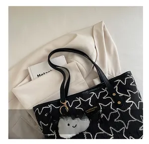 Detail view of black quilted tote bag with star pattern and plush cloud pendant