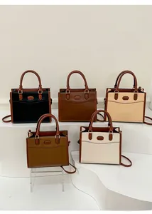 Cinque borse a mano in pelle dai colori classici esposte su un piedistallo bianco