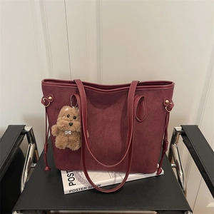 Borsa tote bordeaux retrò con finitura opaca e ciondolo in peluche su sedia di pelle
