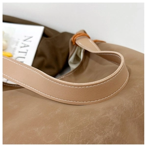 Detailed close-up of brown faux leather tote bag with white stitching and vintage texture
