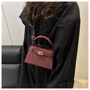 Detail of burgundy leopard print handbag with golden lock worn by a model in black coat
