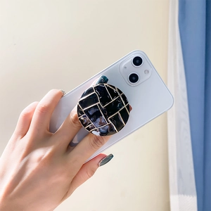 Nahaufnahme eines luxuriösen schwarz-goldenen Handy-Griffs an einem weißen Smartphone