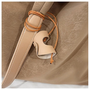 Close-up of textured leather tote bag featuring a knotted strap and gold metal buckle detail