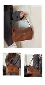 Macro detail of brown leather tote with metal chain strap and flap closure