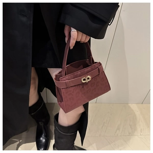 Detail of burgundy leopard print mini handbag with golden twist lock on black coat