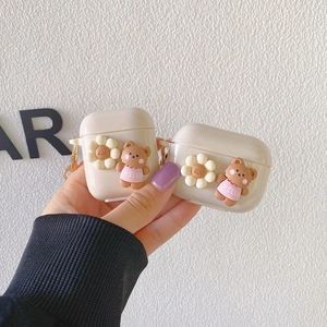 Close-up of silicone AirPods case with 3D brown bear and white daisy flower charms