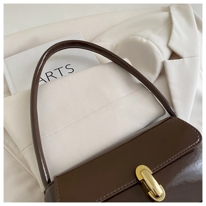 Détail du sac à bandoulière en cuir marron foncé brillant avec fermoir en métal doré