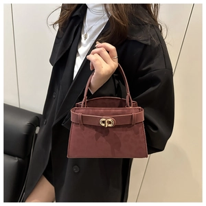 Detail view of burgundy leopard print suede handbag with gold metal clasp on black coat