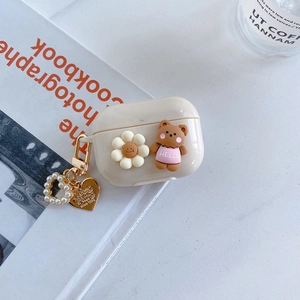 Detail of cream AirPods Pro case with 3D bear, daisy and gold pearl heart keychain