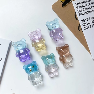 Detail of six gradient resin bear phone stands with gold foil accents on a desk