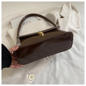 Détail d'un sac à bandoulière en cuir verni marron foncé avec fermoir en métal doré