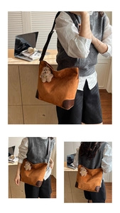 Close-up of brown suede tote bag with black leather straps and cute plush bear charm
