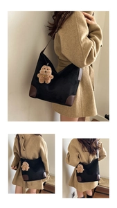 Detail of black tote bag featuring dark brown leather base and plush bear charm