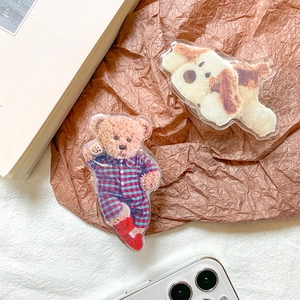 Detail of cute acrylic teddy bear and dog phone grips on a textured white surface