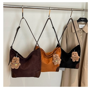 Close-up of hobo shoulder bags in brown and black with plush puppy charms