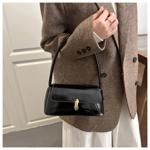 Détail du sac à bandoulière en cuir verni noir brillant avec fermoir en métal doré