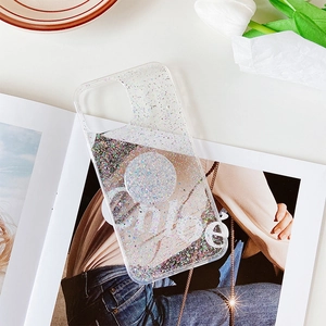 Custodia iPhone trasparente glitterata con supporto rotondo su rivista di moda