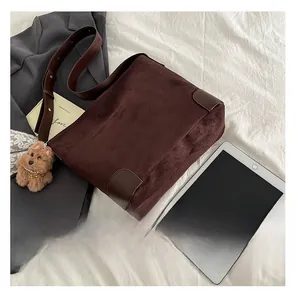 Detail of dark brown suede tote bag with leather corners and plush puppy charm decor