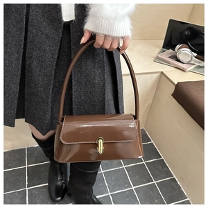 Détail du sac à bandoulière en cuir verni brillant avec boucle dorée et longue poignée