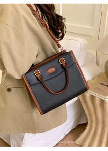Detailed side view of black and brown leather handbag on a model in a minimalist home