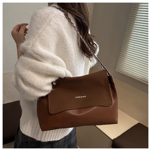 Detail of vintage brown leather tote bag showing the chain strap and fashion print