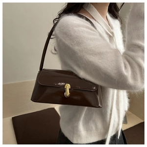 Détail du sac sous le bras en cuir verni marron foncé avec fermoir capsule en métal doré